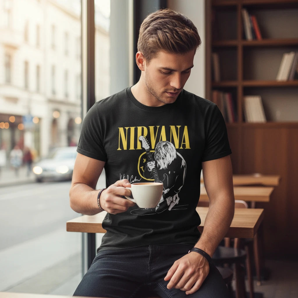 Make It Custom black Nirvana graphic crewneck t-shirt worn by a man holding a coffee cup in a cafe setting.